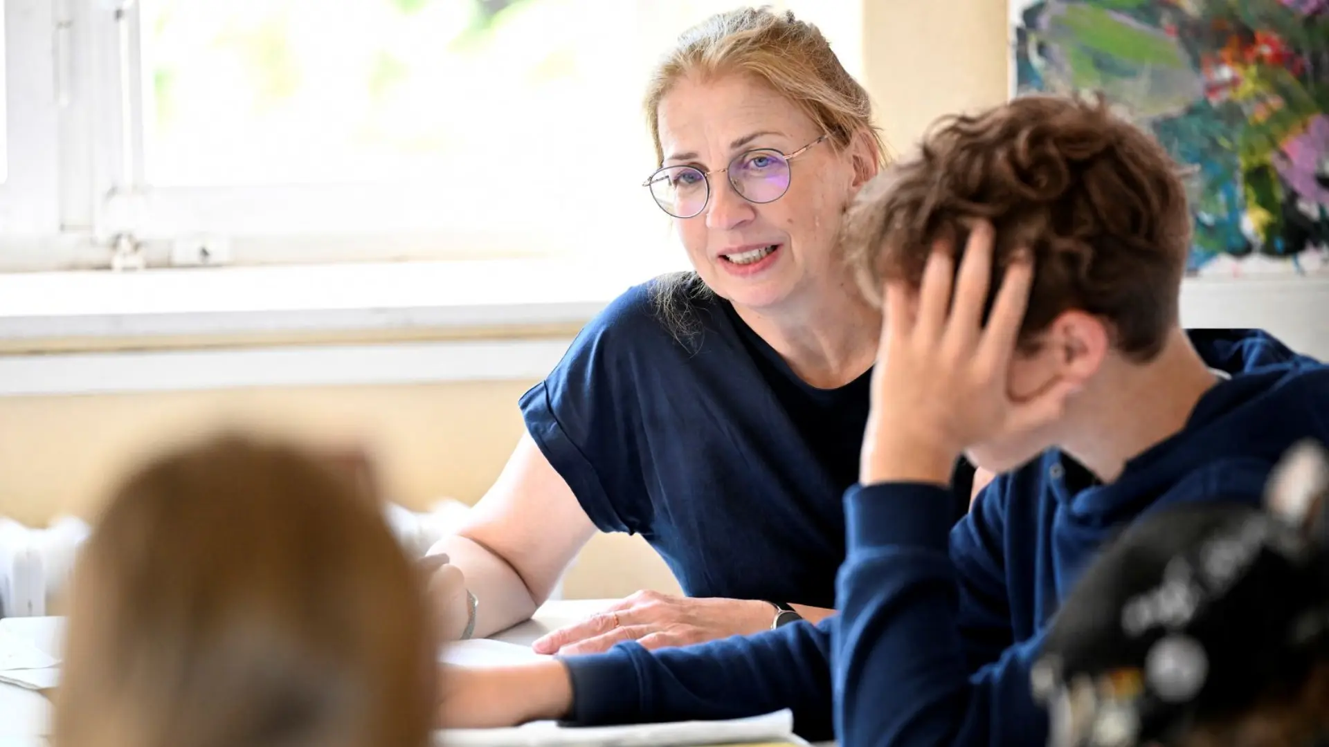 Lehrerin mit jugendlichen Schüler*innen im Gespräch