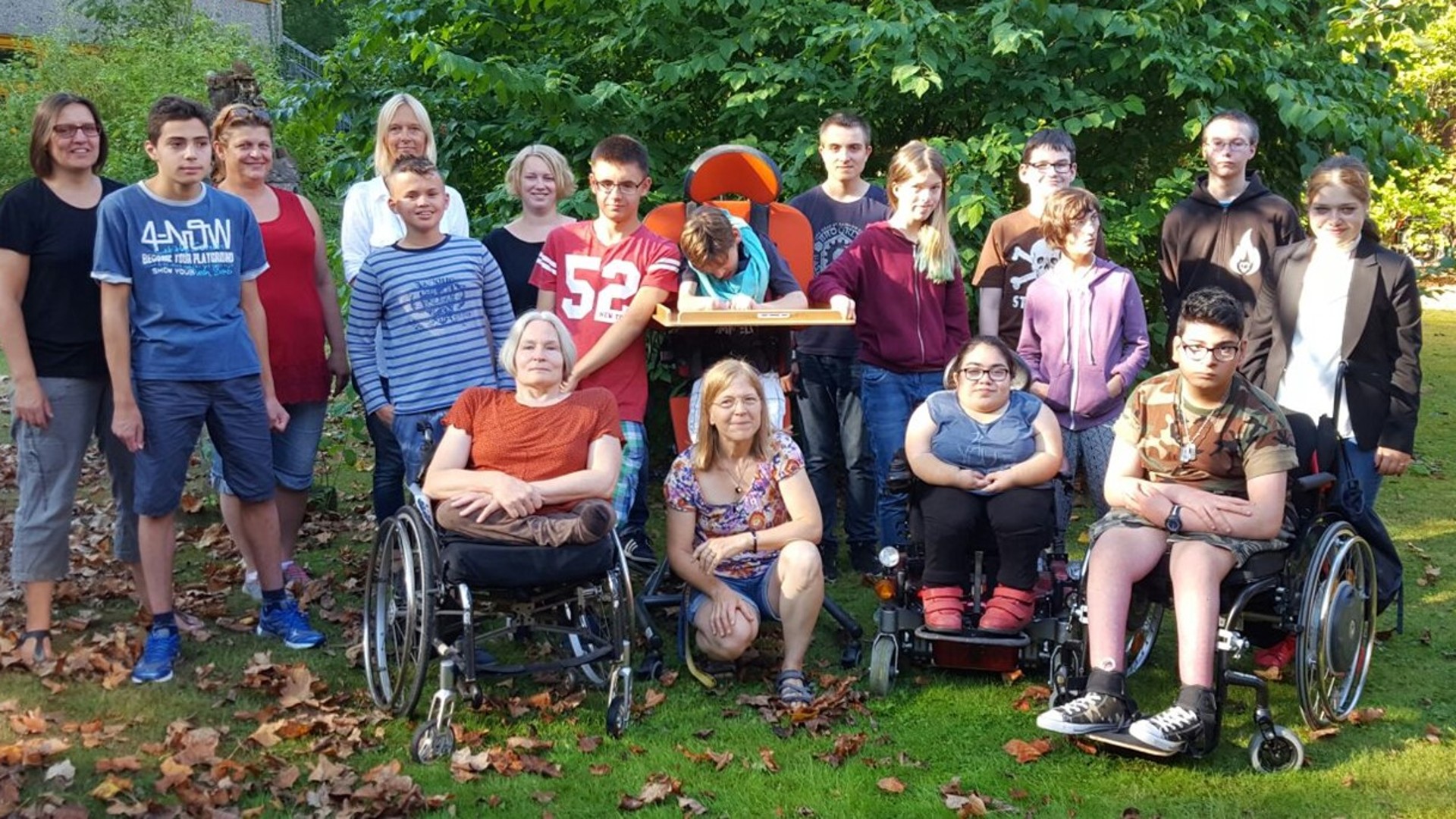 Gruppenbild des Mitglieder des Blauen Blitz: drei Frauen und etwa 10 Jugendliche stehen im Grünen. 4 Personen sitzen im Rollstuhl.