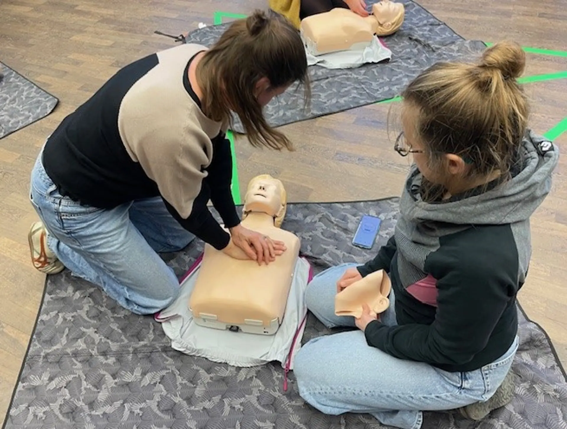 Zwei Personen üben die Herz-Lungen-Massage an einem Dummie.
