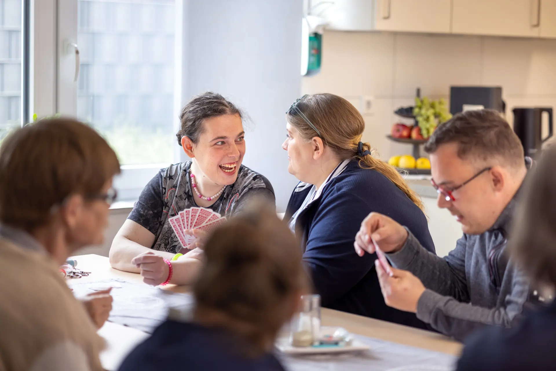 Gruppe von Erwachsenen sitzt an einem Tisch und spielt Karten