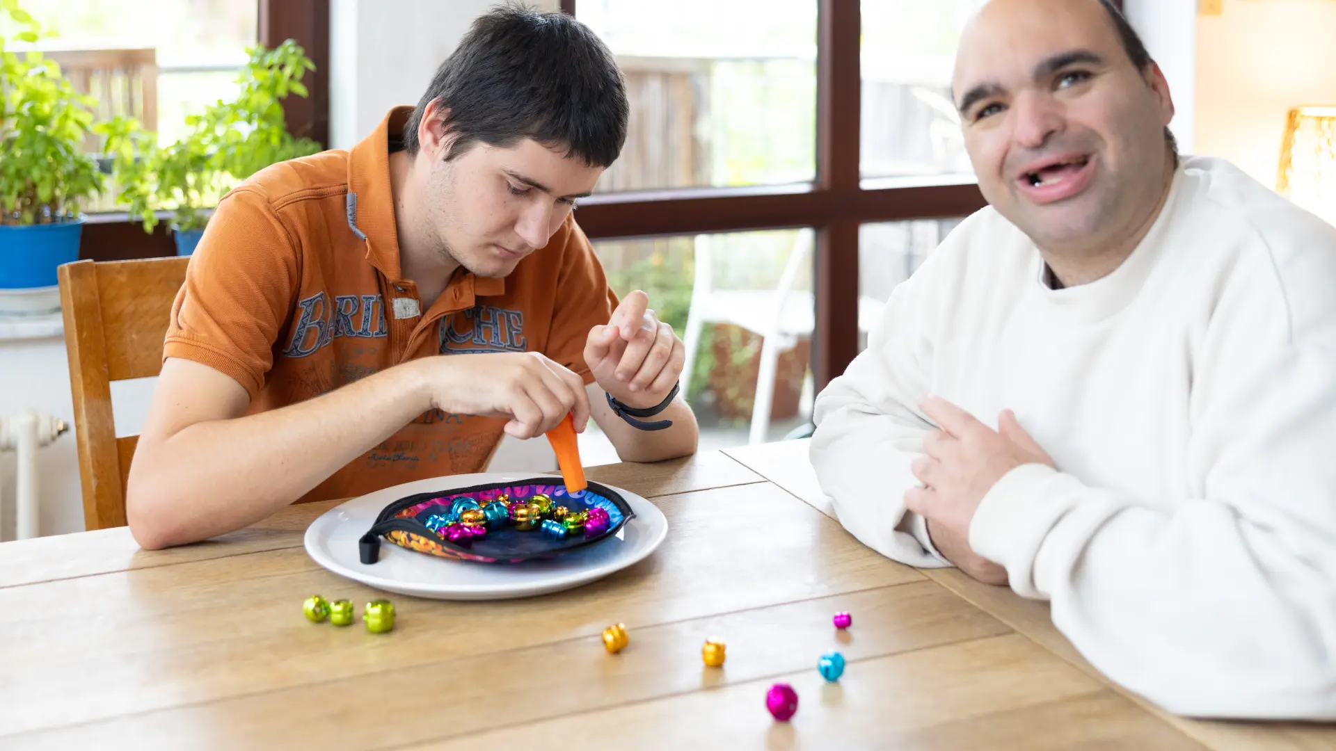 Zwei Männer spielen zusammen ein Geschicklichkeitsspiel am Esstisch.
