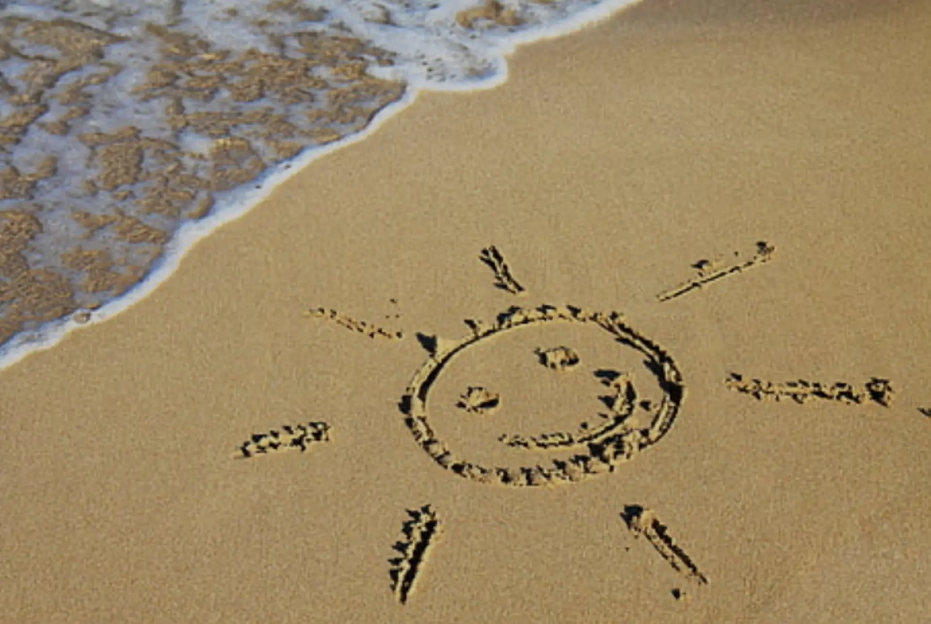 Sand am Strand, darin ist eine Sonne gekritzelt