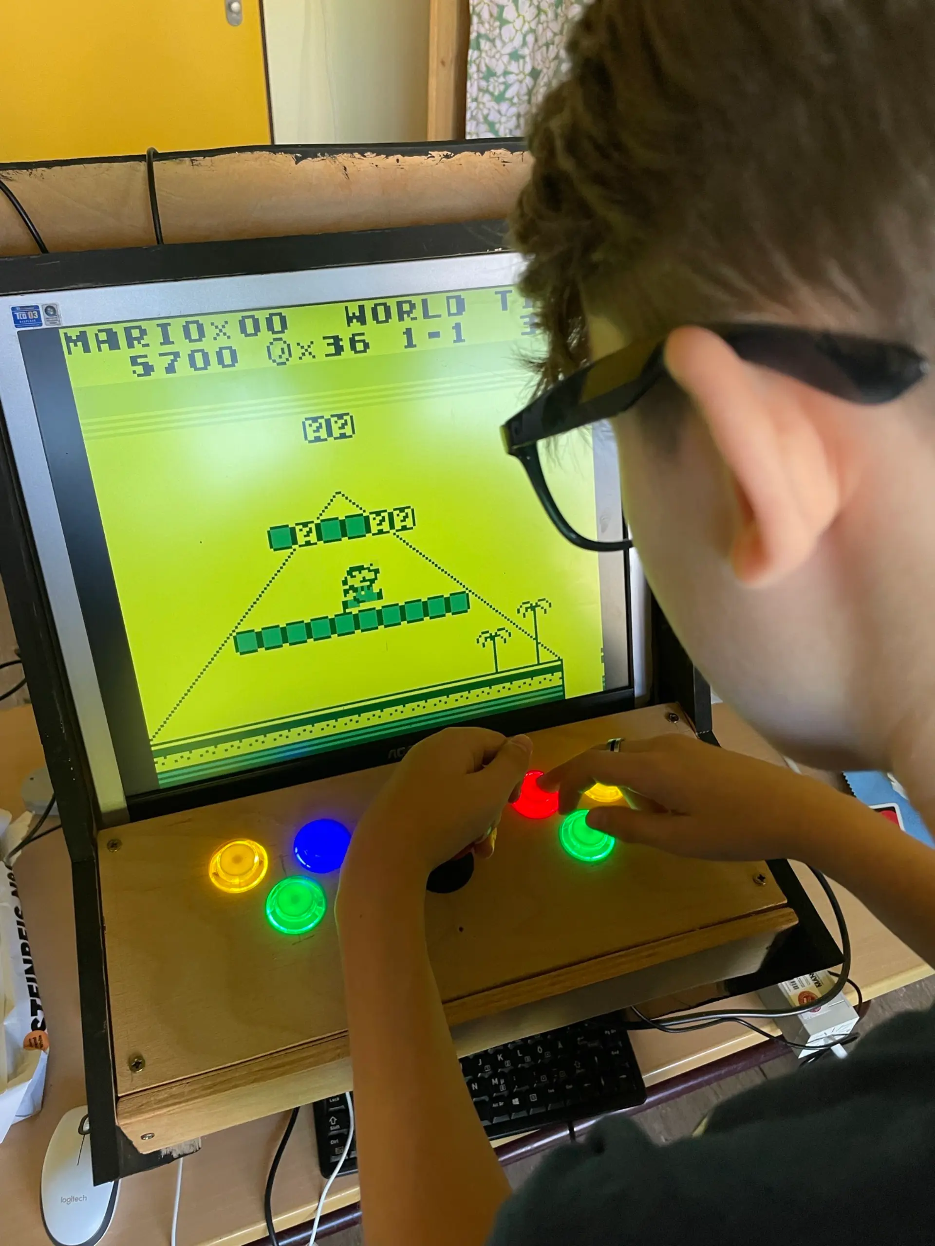 Ein Schüler spielt ein Computerspiel an einer speziellen Konsole mit großen bunten Knöpfen.