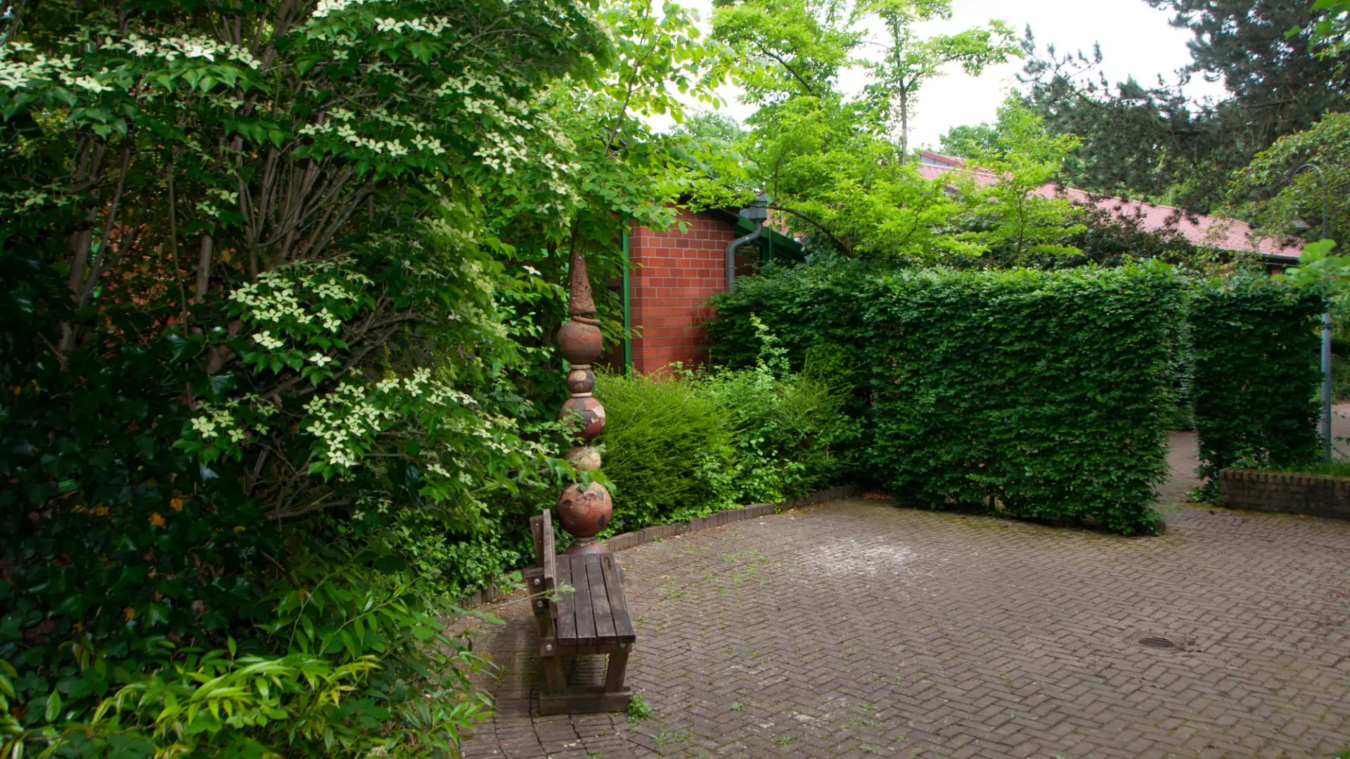 Eine ruhige Ecke im Schulhof mit einer Bank, einer Statue und einem Baum mit Zetteln.