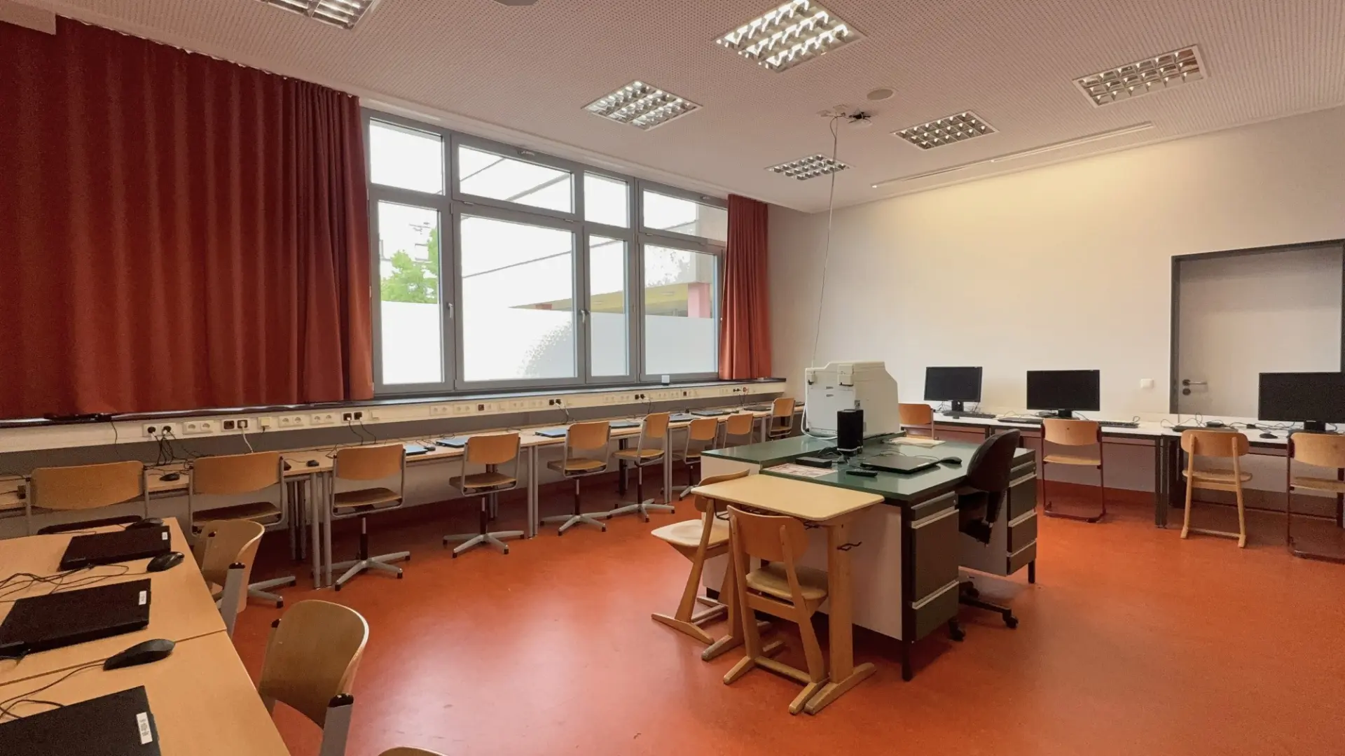 Fachraum mit vielen Tischen entlang den Wänden und Laptops an jedem Sitzplatz