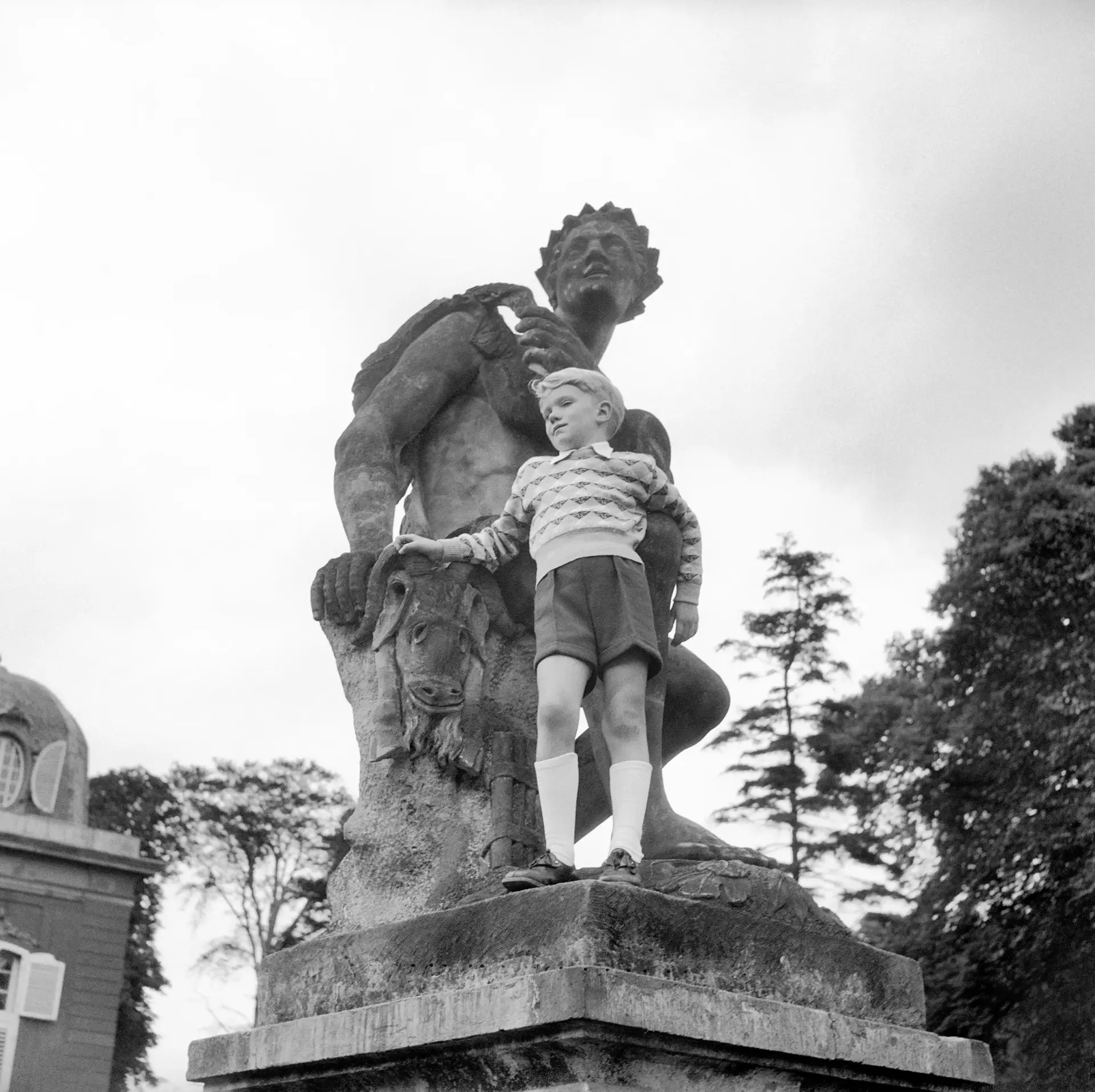 Ein Junge steht vor einer Statue.