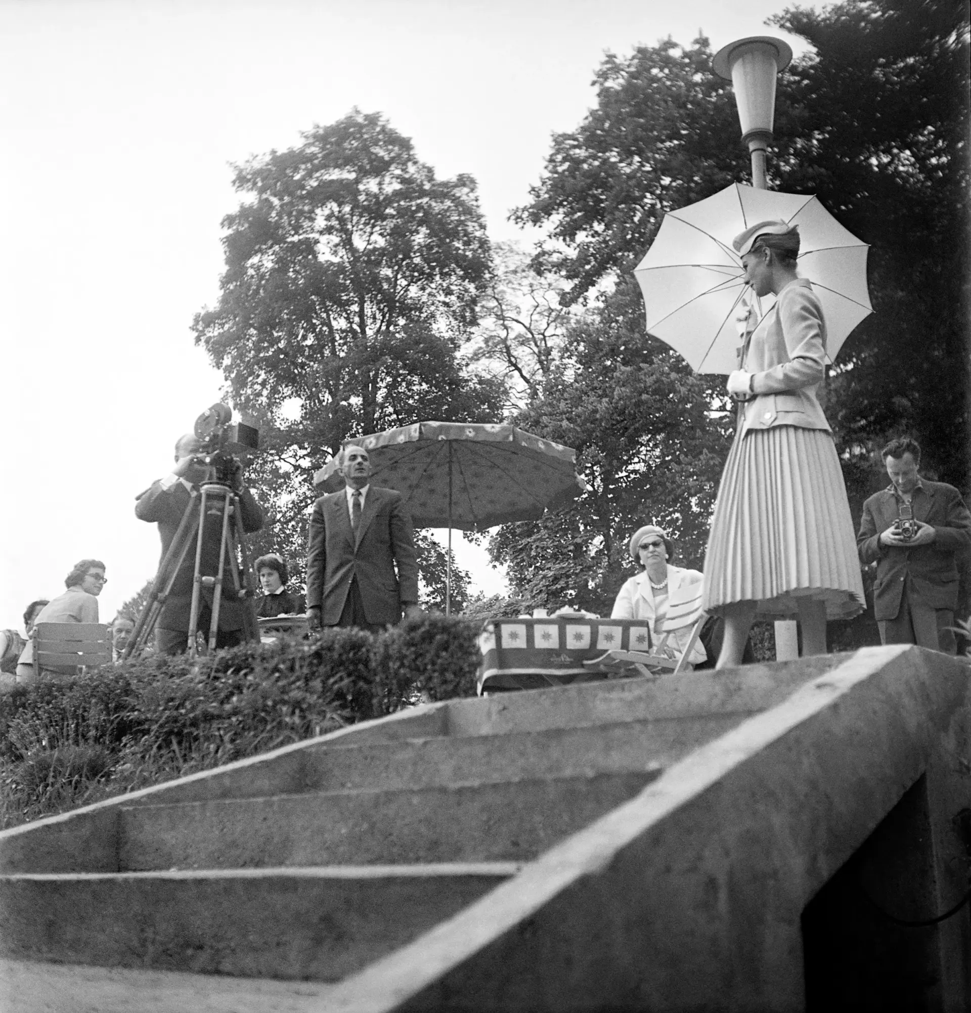 Eine Frau mit einem Sonnenschirm wird gefilmt und fotografiert.