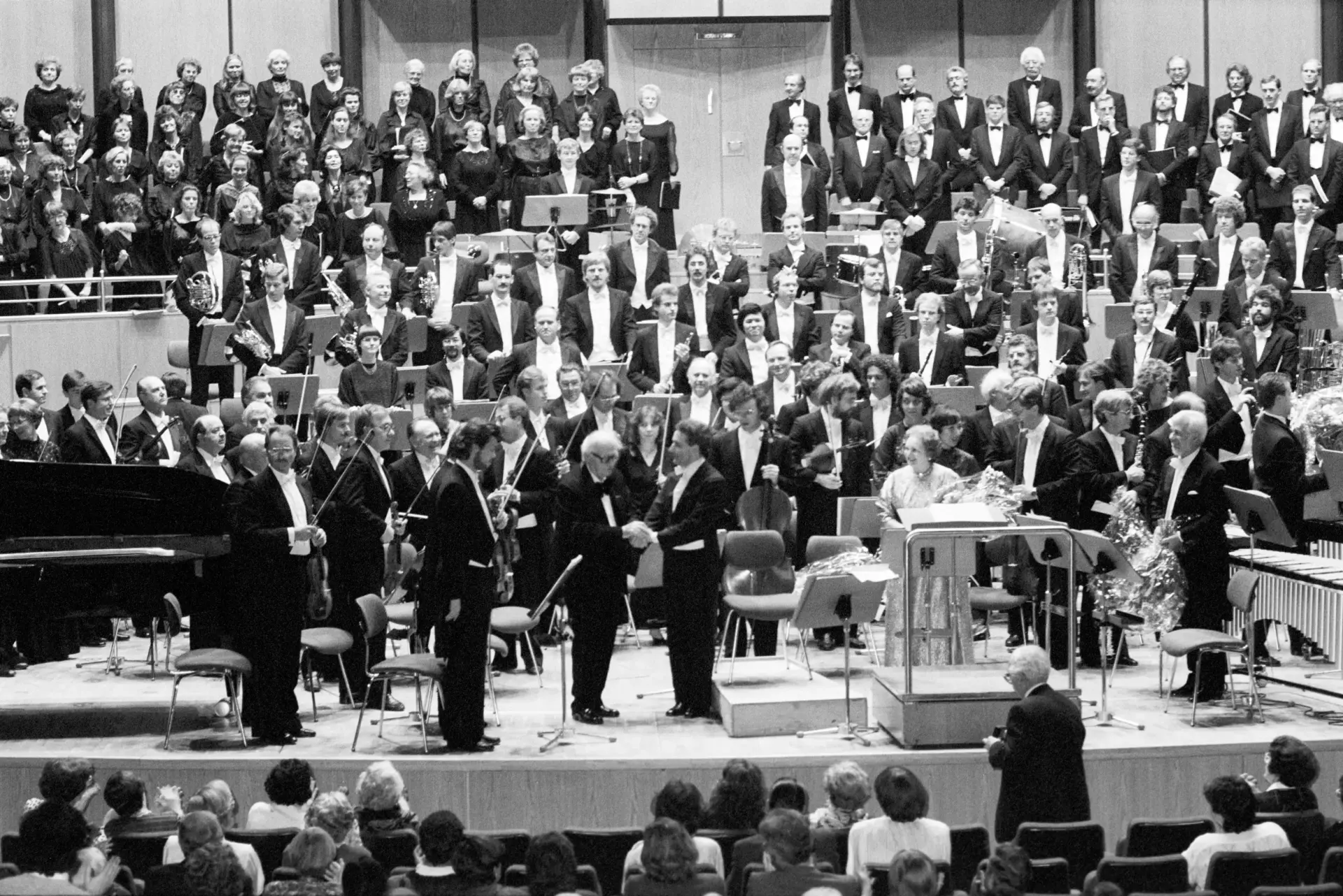 Die Mitglieder eines Orchesters stehen auf einer Bühne.