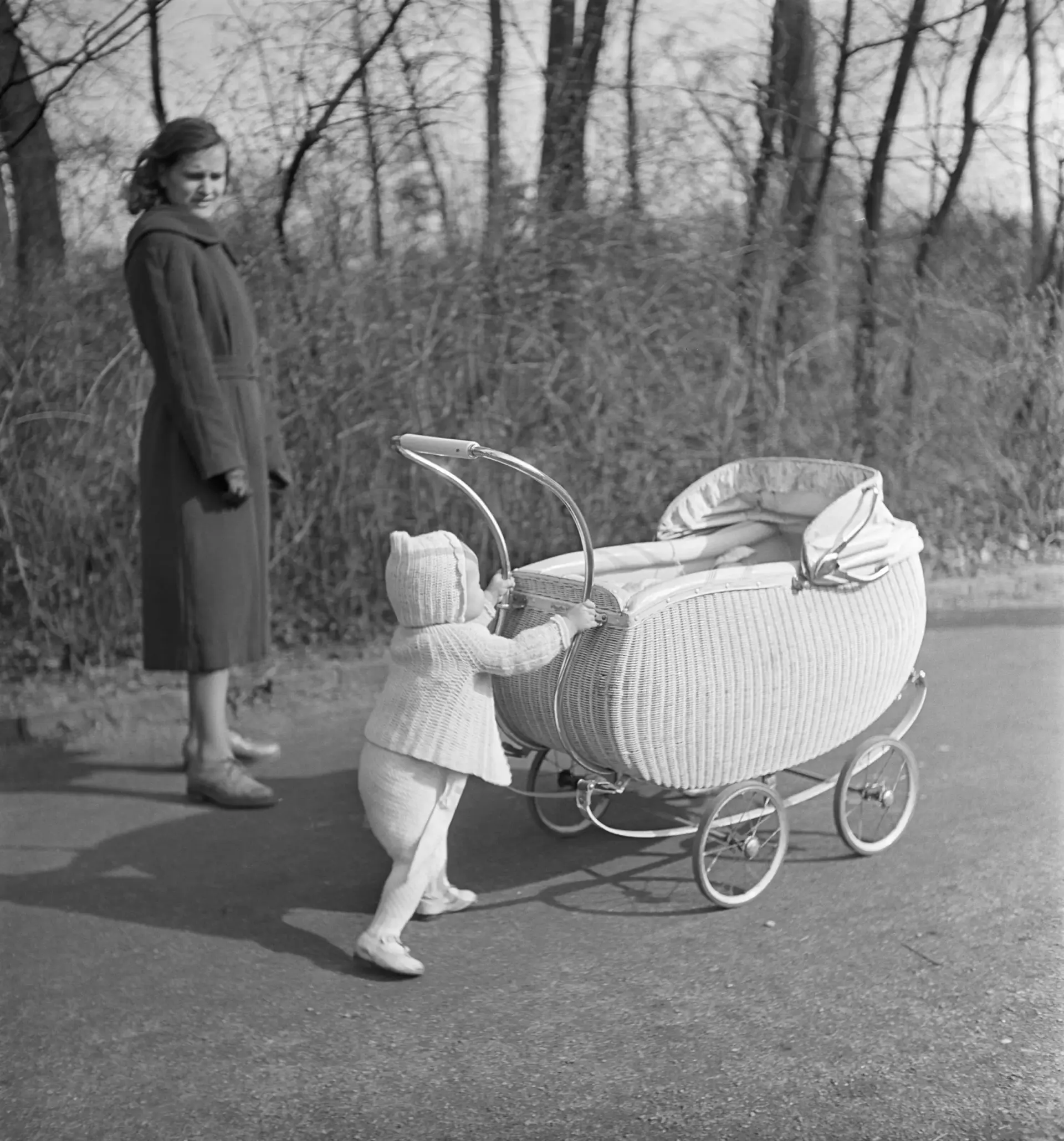 Ein Kind schiebt seinen Kinderwagen.