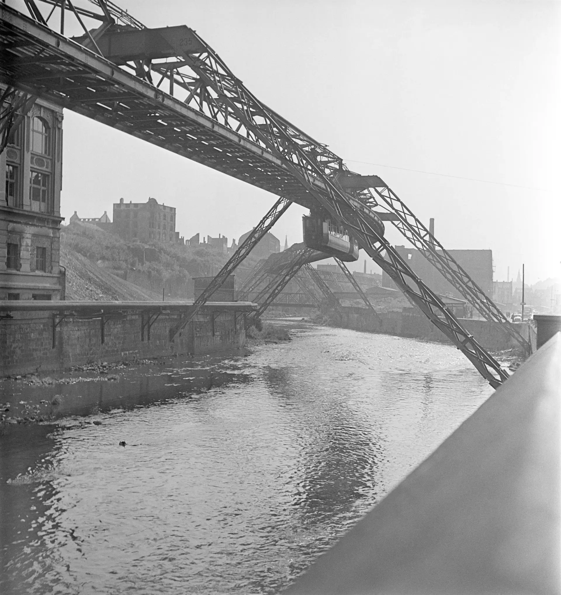 Eine Schwebebahn in einer Stadt, die Kriegsschäden aufweist.