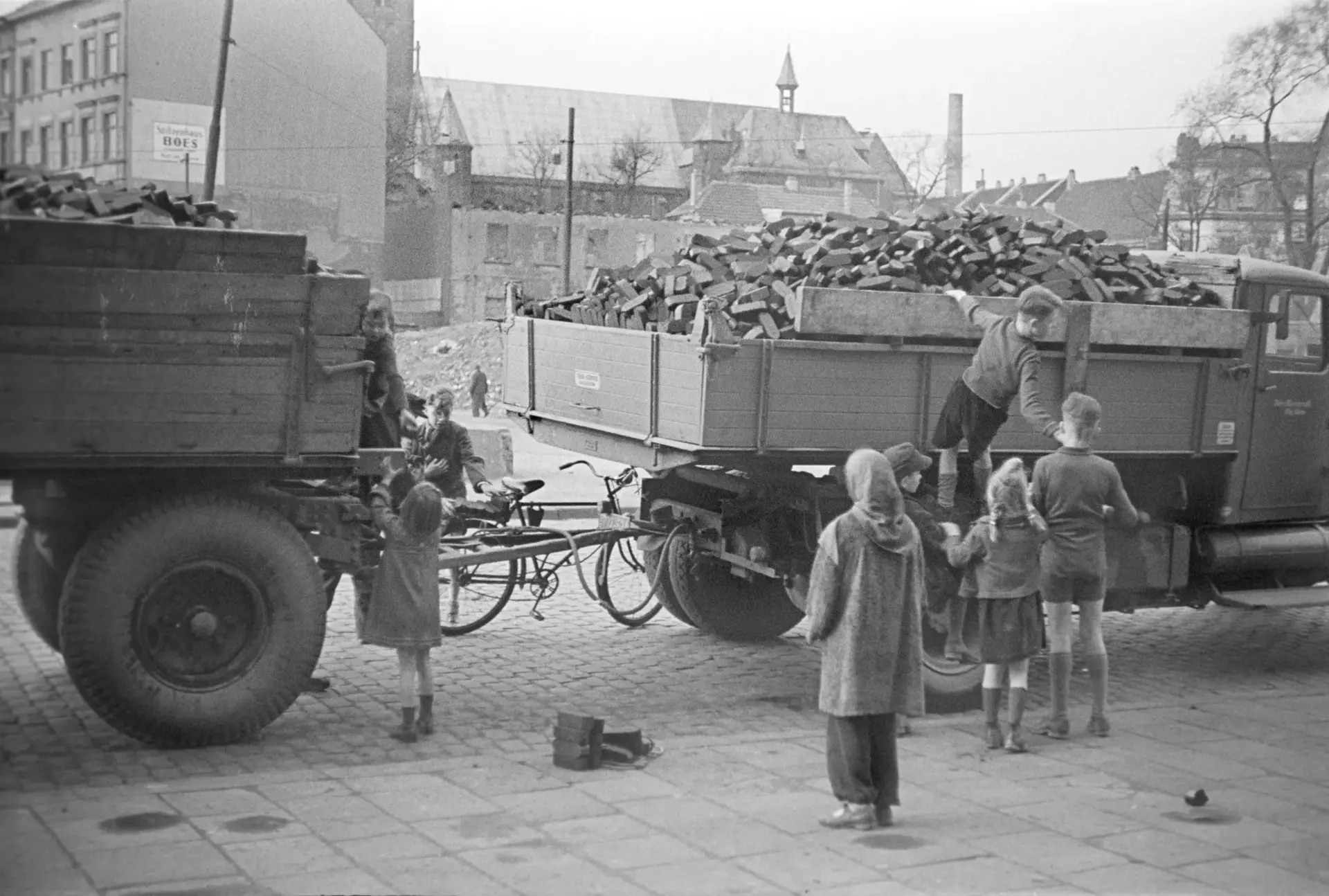 Kinder stehlen Briketts von einem Wagen.