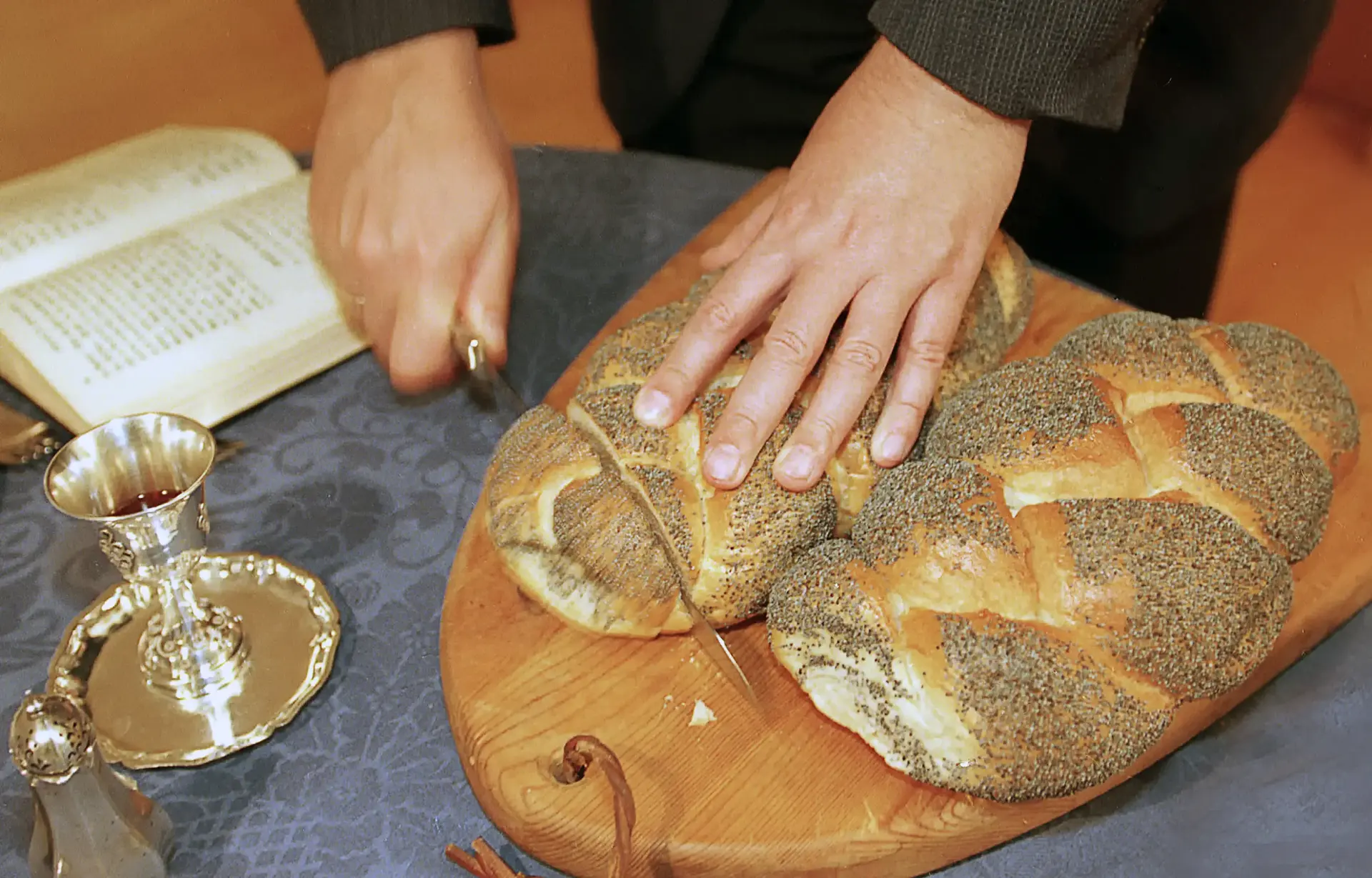 Hände schneiden ein Brot in Scheiben.