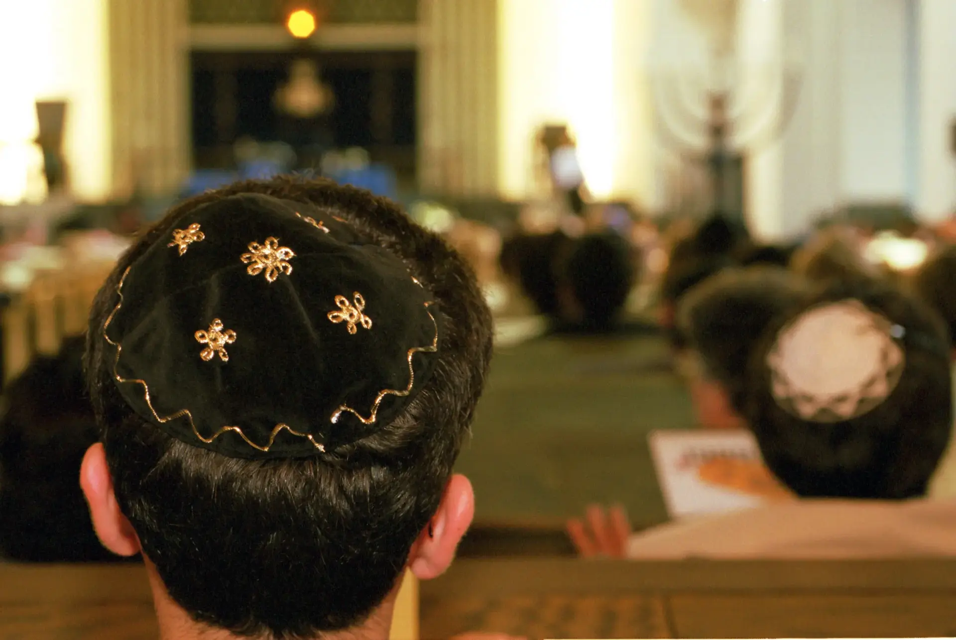 Männer mit Kippot sitzen in einer Synagoge.