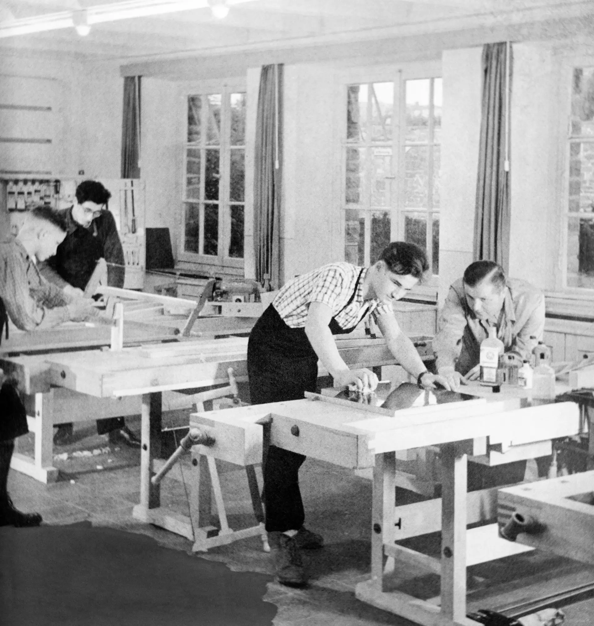 Mehrere Männer arbeiten an Werkbänken.