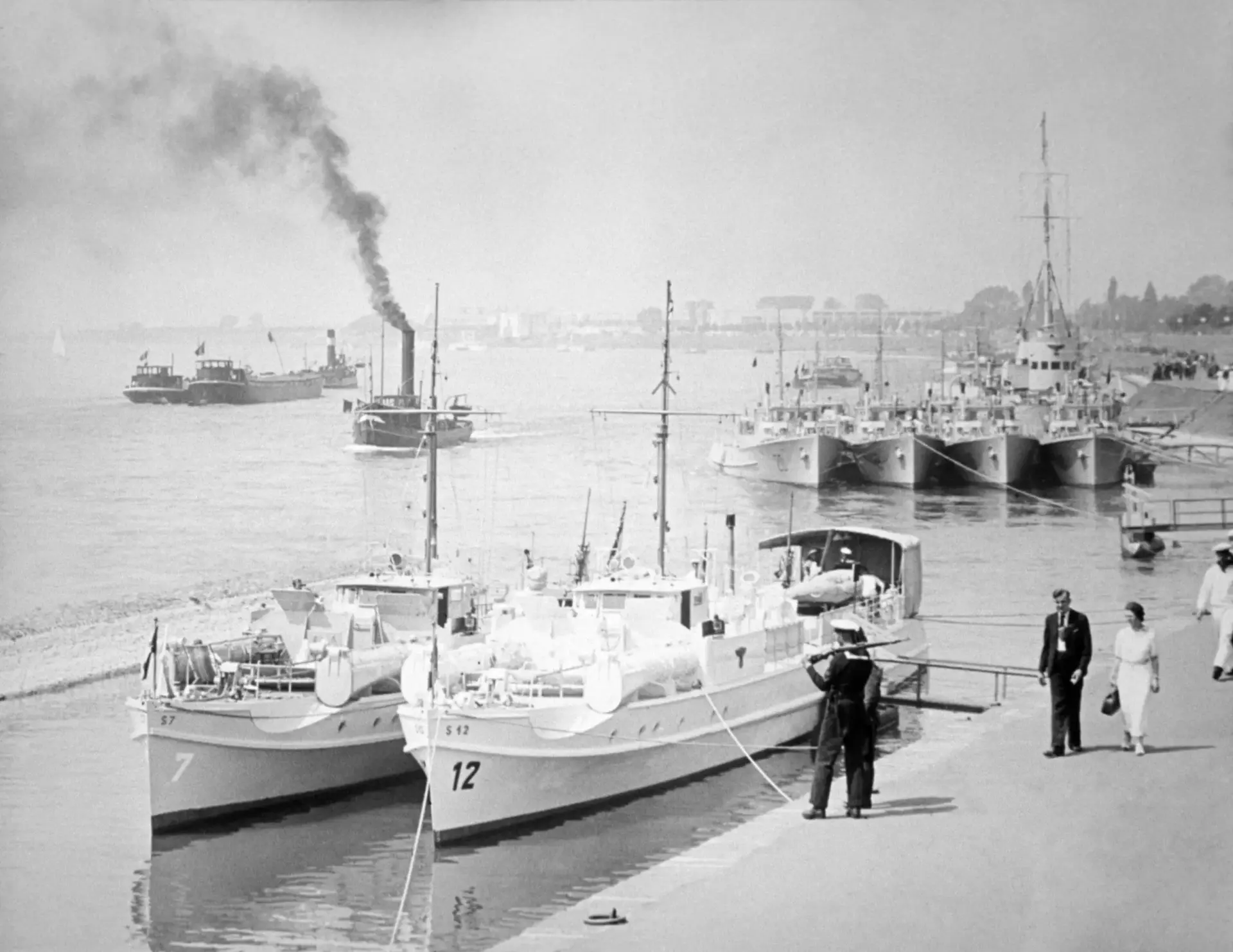 Mehrere Boote der Kaiserlichen Marine liegen in einer Stadt vor Anker.