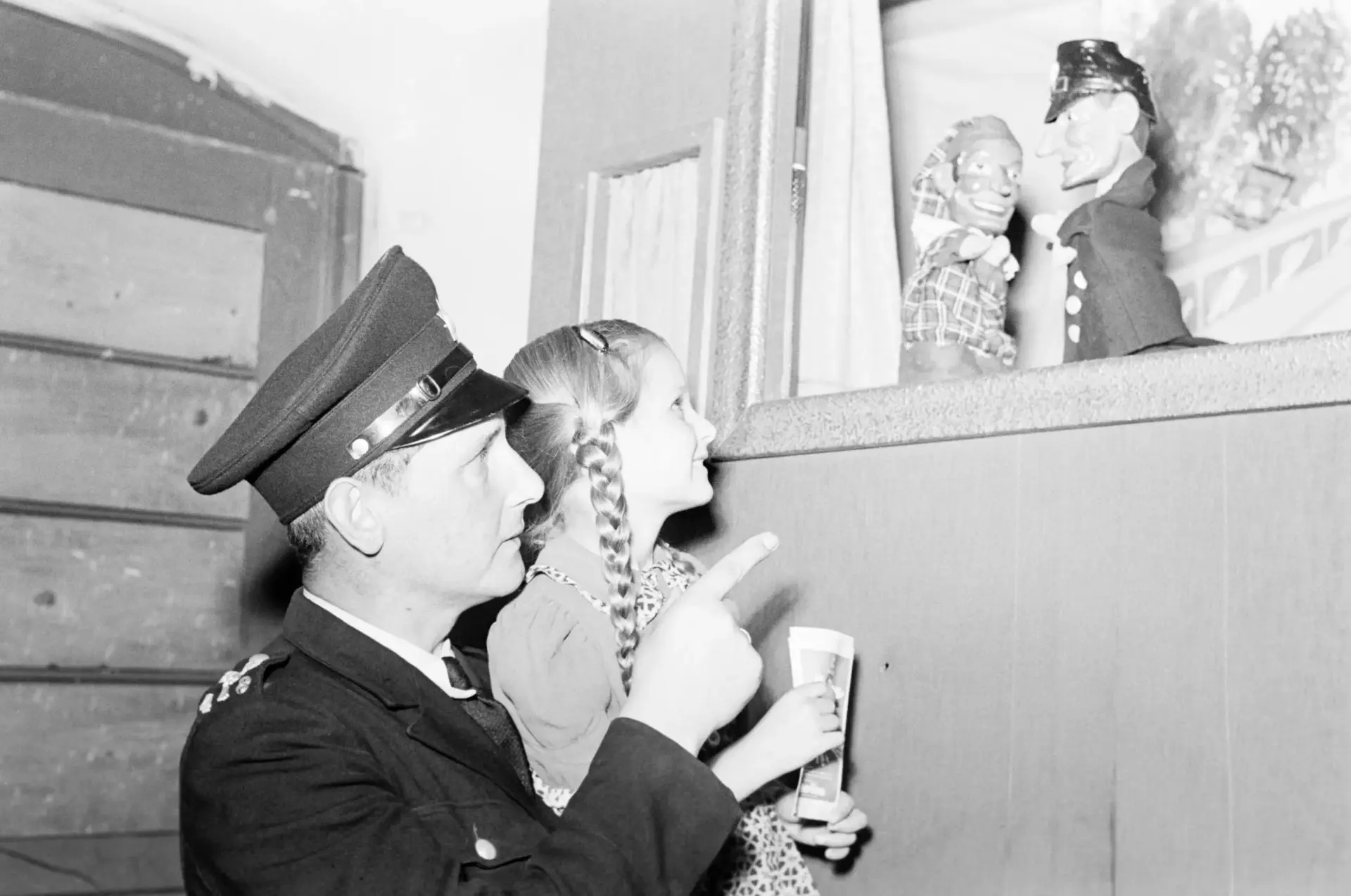 Ein Verkehrspolizist sieht sich mit einem Mädchen ein Puppentheater an.