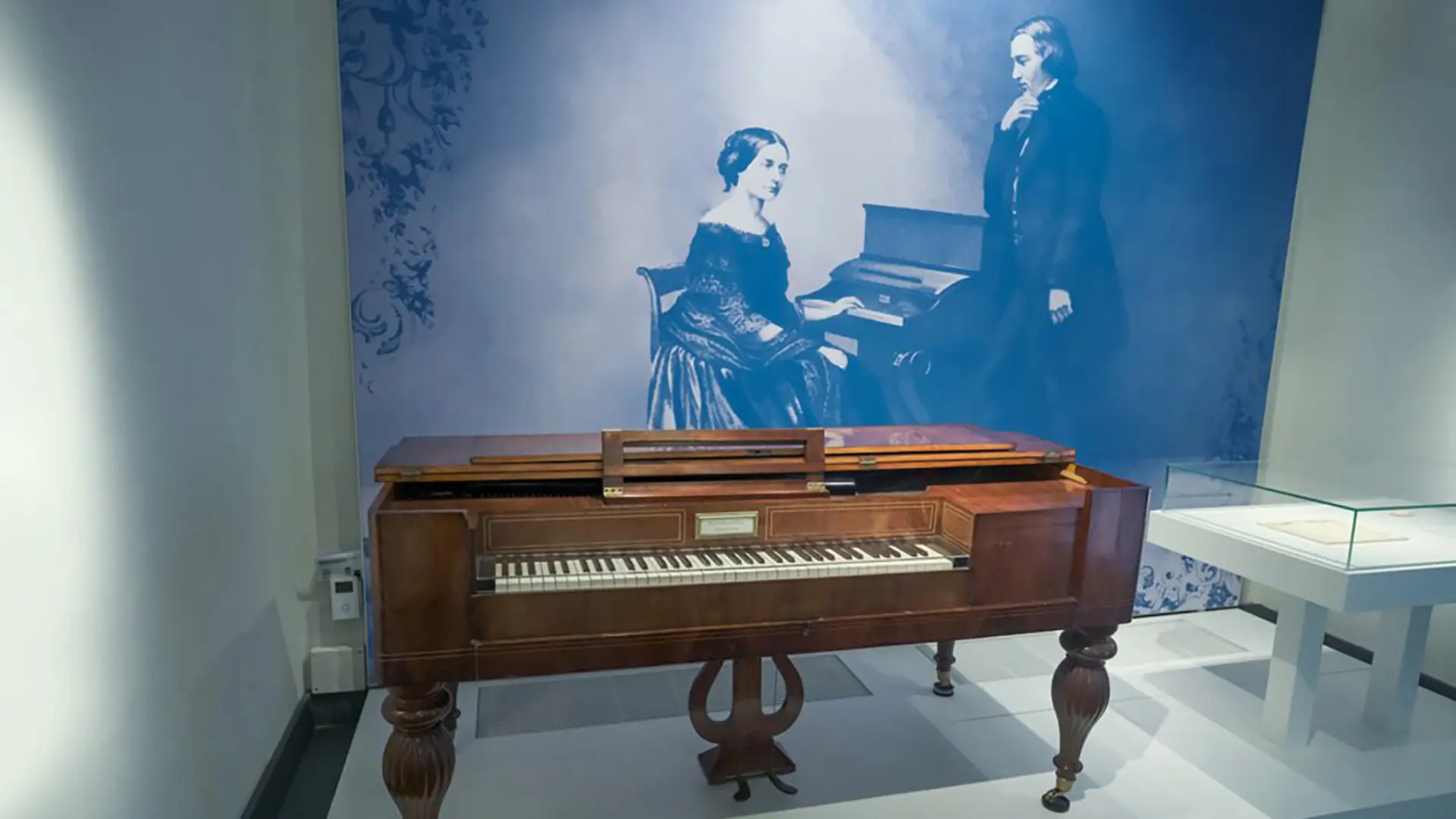 Ein Ausstellungsraum im Schumann-Haus mit einem antiken Klavier und einem Foto des Ehepaares Schumann