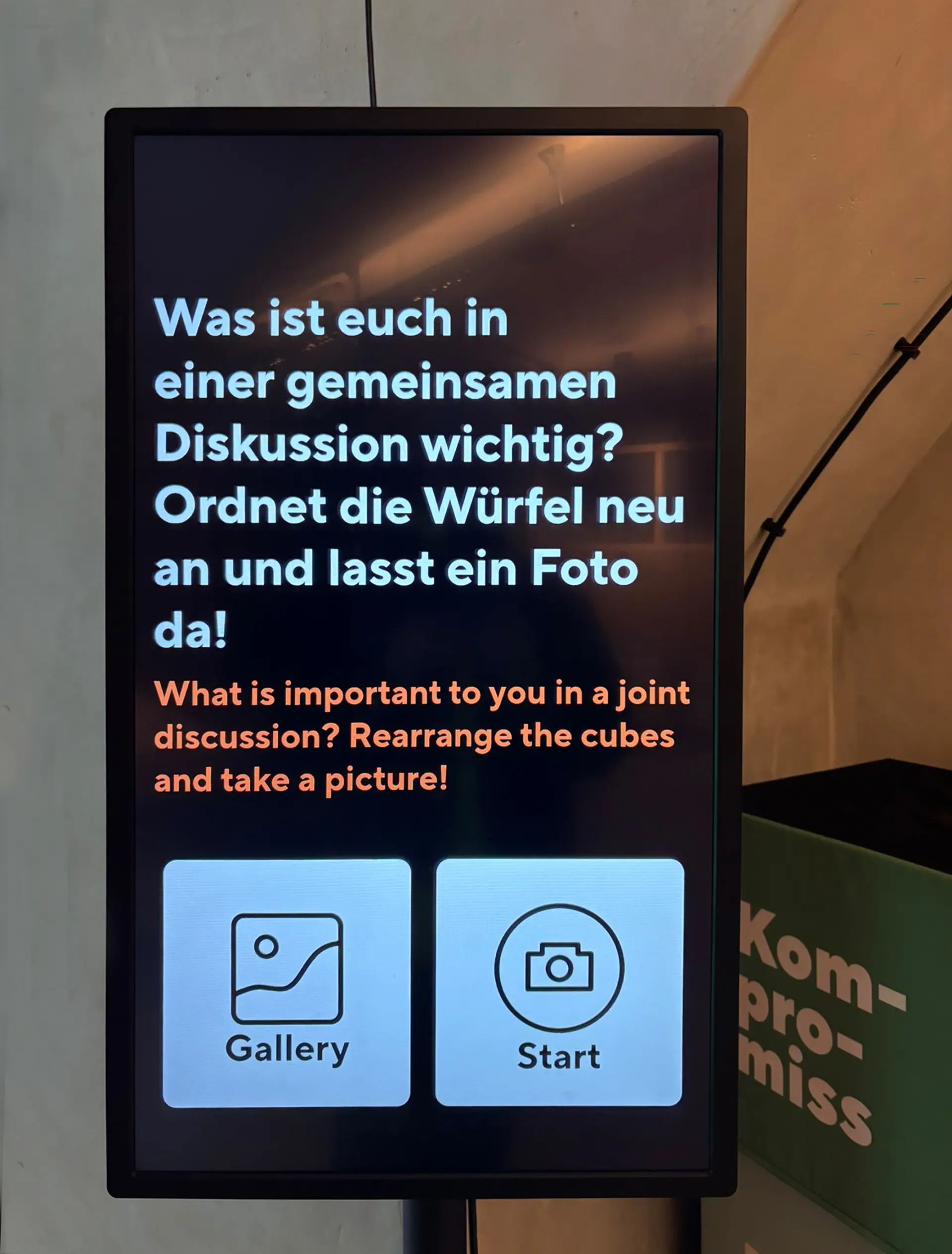 Bildschirm einer interaktiven Station, die zu einer gemeinsamen Diskussion einlädt, sowie Schaltflächen für Galerie und Fotoaufnahme.