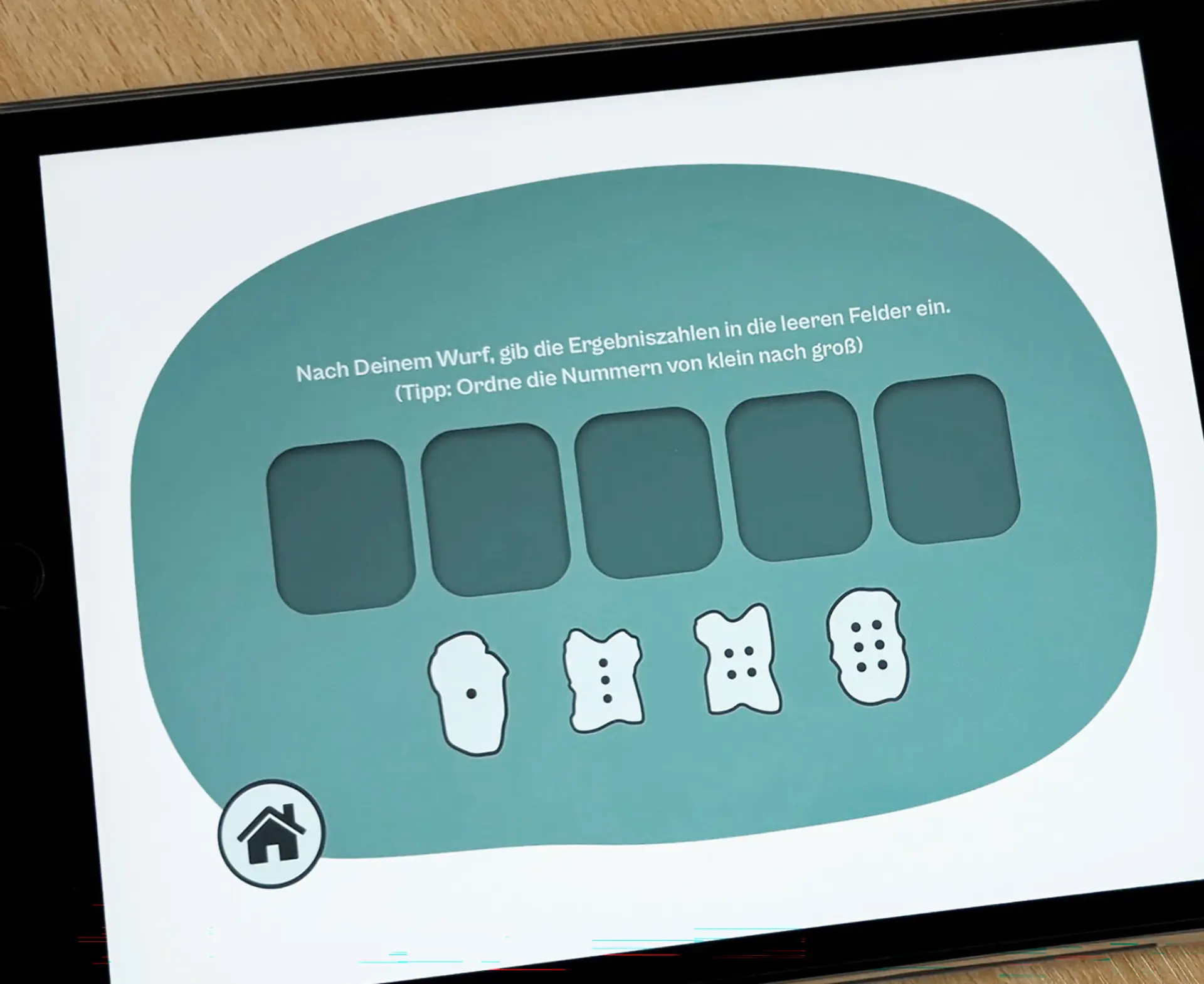 NahauAufnahme eines Tablets mit Lernspiel-App und mehreren kleinen Würfelfiguren auf einem Holztisch